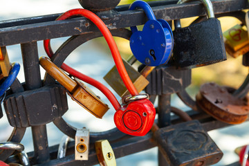 Wall Mural - Close-up on locks of hearts in different colors and shapes hanging on the fence as a sign of eternal love, which is hung during the wedding.