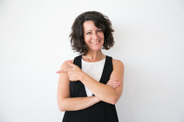 Happy cheerful woman in casual presenting store or product. Middle aged business lady standing over white studio background, pointing finger away and smiling. Advertising concept