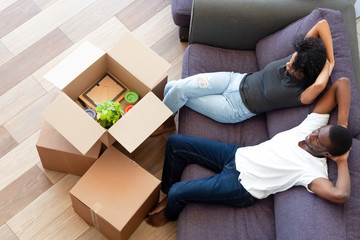 Wall Mural - Above view african couple resting on couch on moving day