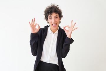 Wall Mural - Excited businesswoman showing ok sign. Emotional middle aged woman in formal wear showing ok sign and smiling at camera isolated on grey background. Gesture concept