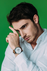 Wall Mural - serious pensive man in white shirt and wristwatch touching face with hand isolated on green