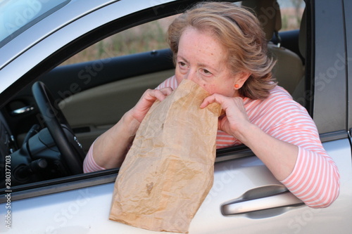 Fotografía Mature female driver vomiting in paper bag