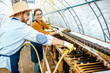 © rh2010 - Man and woman working in the hothouse on a farm for growing snails, washing shelves with water gun. Concept of farming snails for eating