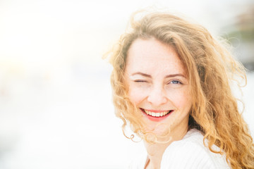 Beautiful ,elegant, teenager, with red hair and freckles,wearing a white dress and a hat, enjoy the seaside resort, sunny day on the beach, she winks,and smiles,lightflare