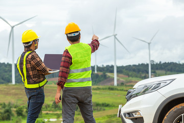 two windmill engineer inspection and progress check wind turbine at construction site by using a car