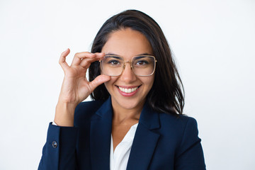 Wall Mural - Content businesswoman adjusting eyeglasses. Portrait of beautiful young businesswoman wearing eyeglasses and smiling at camera. Business concept