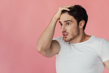 Wall Mural - shocked muscular man in white t-shirt touching head isolated on pink