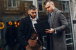 © prostooleh - Two handsome men working. Friends talking. Man in a suit and coat