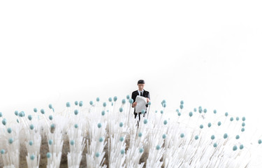 miniature person lost in a field, businessman looking at a map while standing on a hair brush