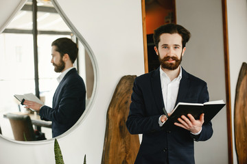 Wall Mural - Handsome man in a black suit. Businessman working in a office