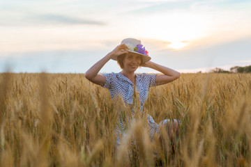 Wall Mural - Free and happy woman in dress and hat on wheat field. Freedom, joy concept.