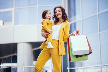 Beautiful girl in a summer city. Lady with shopping bags. Mother with daughter in stylish clothes