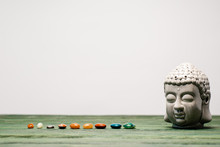 Buddha Statuette And Colorful Semiprecious Stones On Wooden Surface Isolated On Grey