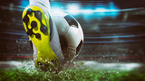 Fototapeta Sport - Football scene at night match with close up of a soccer shoe hitting the ball with power