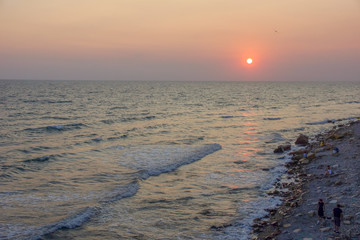 Wall Mural - seascape sunset the sun sets the sea wave the sea foam. stones coast