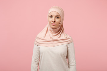 Beautiful young arabian muslim woman in hijab light clothes posing isolated on pink background studio portrait. People religious Islam lifestyle concept. Mock up copy space. Standing, looking camera.