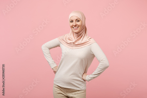 Cuadros en Lienzo Smiling young arabian muslim woman in hijab light clothes posing isolated on pink background studio portrait