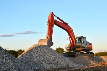 Poster - Large tracked excavator works in a gravel pit. Loading of stone and rubble for its processing at a concrete factory into cement for construction work. Cement production factory on mining quarry