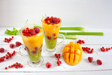 Fototapeta Fototapety do kuchni - Kolorowe wielowarstwowe smoothie z mango, kiwi, selerem naciowym, porzeczkami i malinami