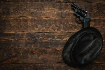 Wall Mural - black leather hat and gun on a wooden table of detective agent flat lay background with copy space.