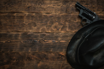 Wall Mural - black leather hat and gun on a wooden table of detective agent flat lay background with copy space.