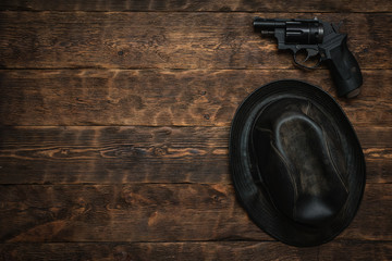 Wall Mural - black leather hat and gun on a wooden table of detective agent flat lay background with copy space.