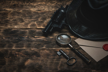 Wall Mural - top secret envelope, gun, leather hat, key and magnifying glass on a wooden table of detective agent