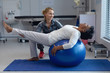© Wavebreak Media - Physiotherapist helping patient on exercise ball in hospital