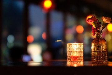 Close up candle light and flower on table. Defocused colorful lights background. Bar and restaurant concept