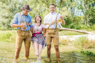 Wall Mural - friends having fun on Bavarian RIver(isar) Two men carry woman over the river