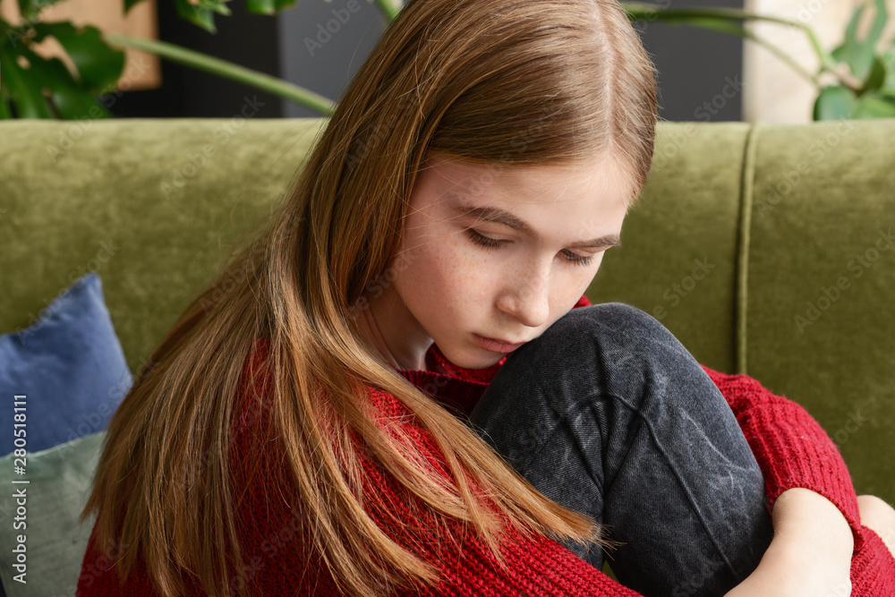 Sad teenage girl sitting on sofa at home Stock Photo | Adobe Stock