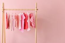 Rack With Hanging Clothes On Color Background