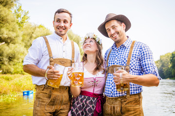 Poster - Freunde in bayerischen Tracht feiern an der Isar und trinken Bier. Oktoberfest München