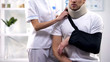 Female surgeon adjusting male patient arm sling, orthopedics and rehab period
