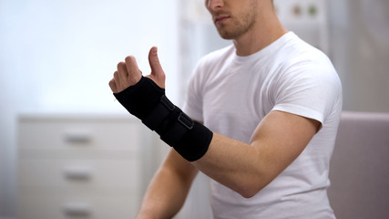 Male looking at hand with titan wrist support, orthopedic equipment, trauma