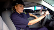 Concentrated female officer driving in underground parking, monitoring order