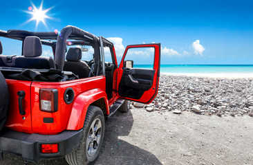 Poster - A red jeep on sandy beach and beuatiful blue sunny sky view in summer time.