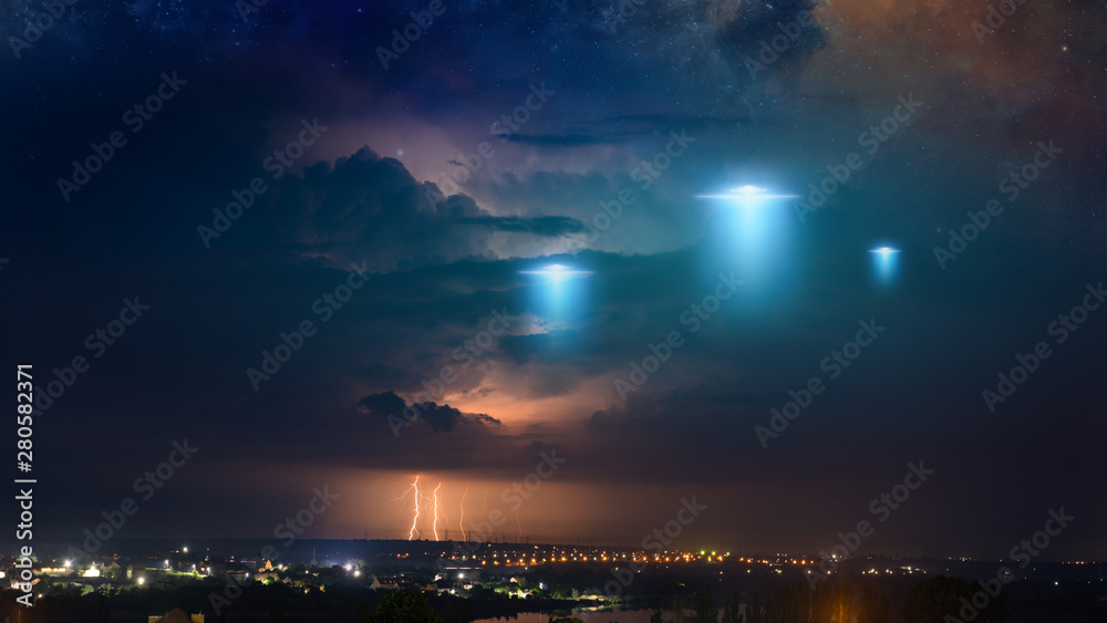 Extraterrestrial aliens spaceship fly above small town, ufo with blue spotlights in dark stormy sky. - obrazy, fototapety, plakaty 