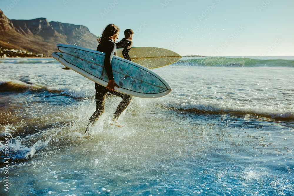 To young surfers going for water surfing - obrazy, fototapety, plakaty 