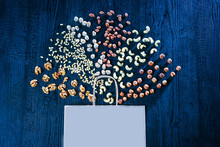 Nuts And Paper Bag On Blue Background. Selling Nuts. Walnuts, Pine Nuts,pistachios, Cashews, Hazelnuts Laid Out On The Table. Trade Nuts. Snacks. Food Industry