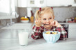 Young girl drinking milk and eat healthy breakfast at the kitchen table