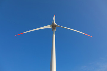 wind turbine with sun flare blue sky background view from below