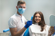 © studioprodakshn - young brunette woman patient and dentist in blue gloves medical mask and safety glasses satisfied with treatment results in dental clinic