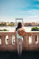 Rear view of young woman with backpack and hat, traveling in the Budapest city, Hungary