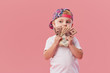 © oes - Portrait of a cheerful little toddler boy in cap holding a dollars money over pink background