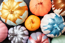 Bright Pumpkins Painted In Different Colors Presented On A Dark Concrete Background With Reflection Of Shadows. Halloween Card