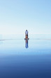 © Trinette Reed/Stocksy - Woman meditating by swimming pool with her husband greeting her