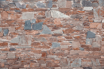 Wall Mural - The wall of different colored natural stones forms a mosaic and a background