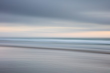 The Blurred Wash Of The Sea Below A Cloudy Sky.