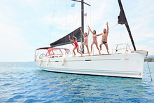 Friends Hanging Out, Having Fun And Enjoying Summer Days Jumping From Sailing Boat In Sea. .